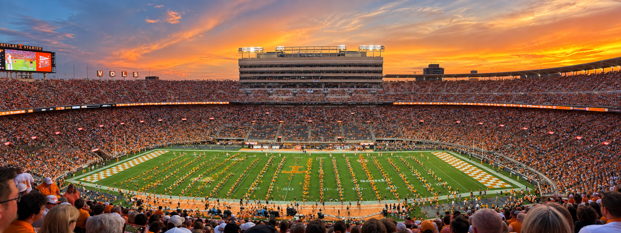 Merged panorama of Neyland Stadium at sunset, with Tennessee fans and the marching band on the field